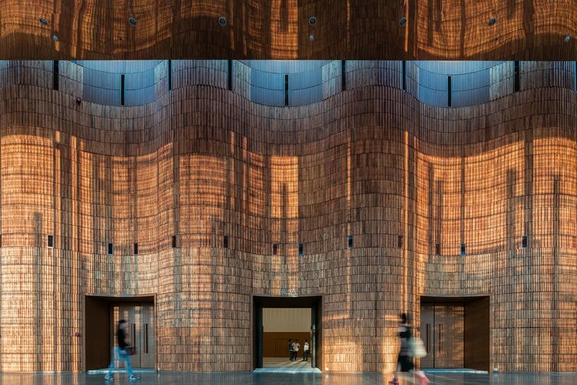 undulating wooden panels form veil-like facade in vietnamese conference center