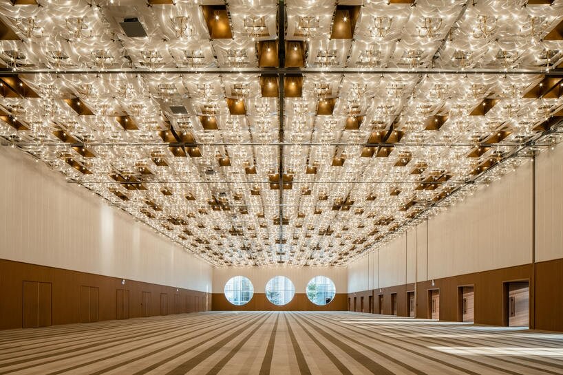 undulating wooden panels form veil-like facade in vietnamese conference center