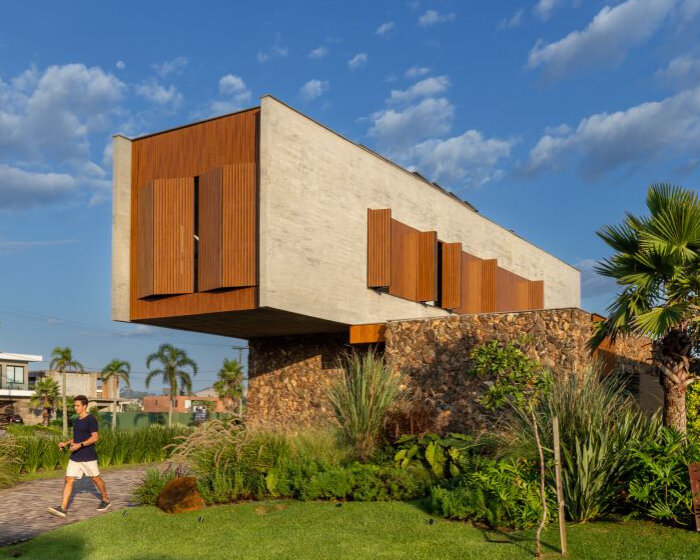 oficina conceito arquitetura's cantilevering house protrudes from stone volume in brazil