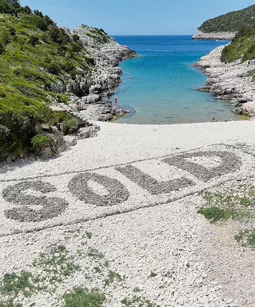 dark stones spell SOLD on greek beach in protest against coastal development
