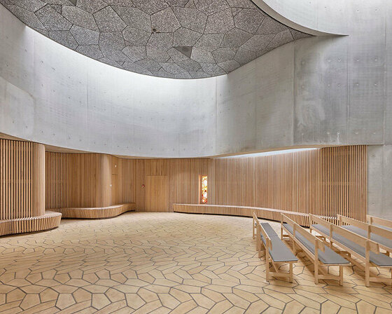 fluid concrete shell wraps warm timber interiors of denmark's trekroner church