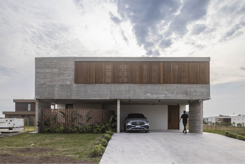 Parasoles regulables dan vida a la fachada rústica de una casa argentina diseñada por TIM arquitectos