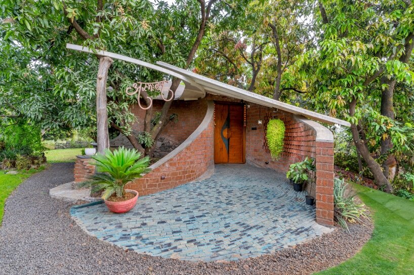 curved brick walls wrap biophilic farmhouse by blurring boundaries in mumbai mangro grove