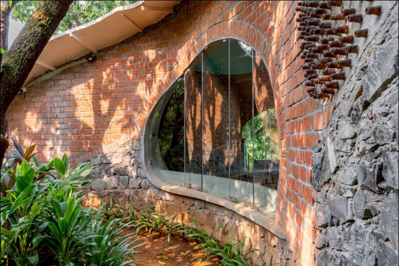 curved brick walls wrap biophilic farmhouse by blurring boundaries in mango grove in india