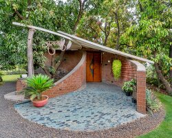 curved brick walls wrap biophilic farmhouse by blurring boundaries in mango grove in india