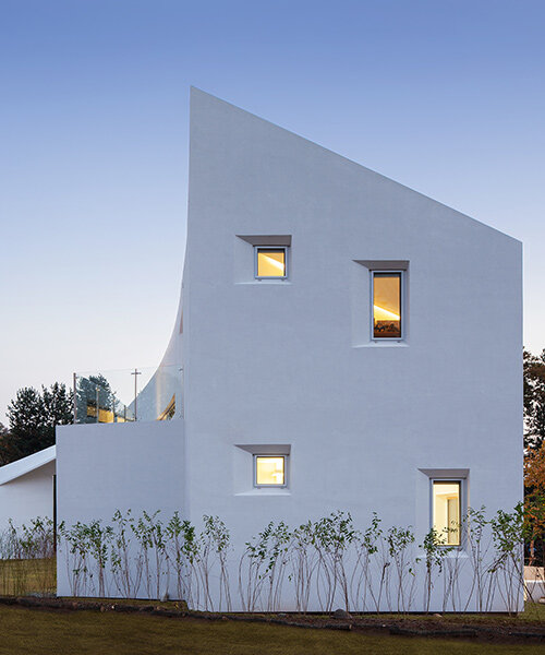 curvilinear house in south korea sweeps toward the ground with fluid facade