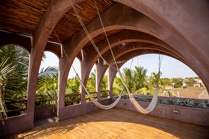 palm trees become part of casa onda's arched facade in guatemala surf town