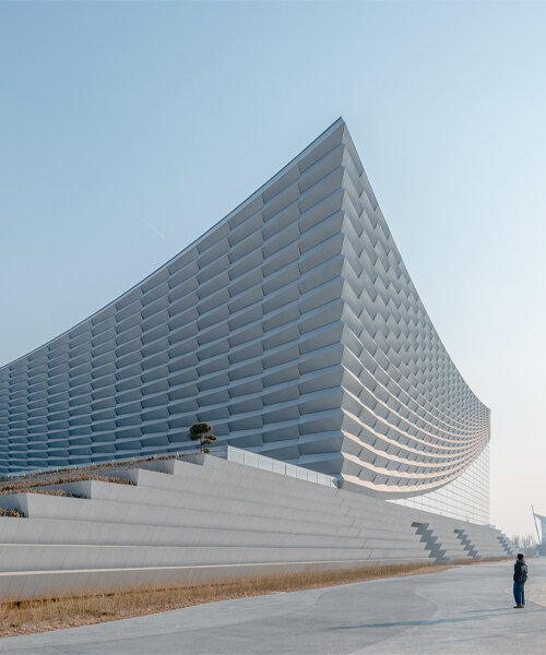 beijing performing arts centre rises from broad plinth like parting theater curtains