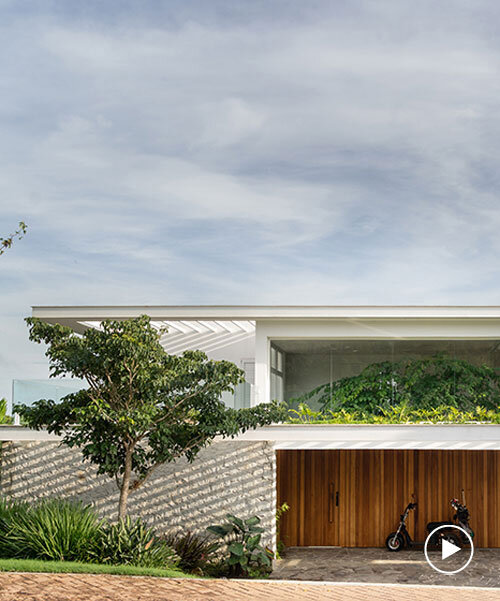 two vertical planes of white wood stone enfold casa búzios' volumes in rio de janeiro