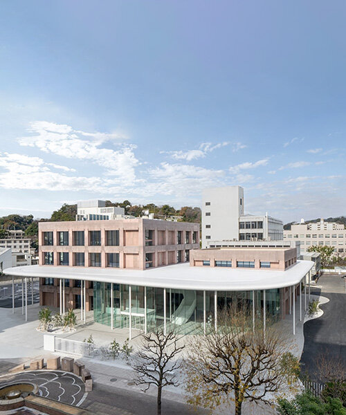 colored concrete buildings emerge from cloud-like floating roof at japanese campus