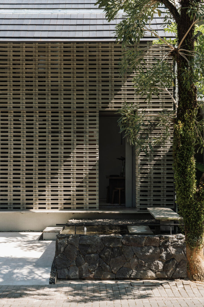 interlocking spaces behind perforated brick facade turn home into an office by dhanie & sal in indonesia