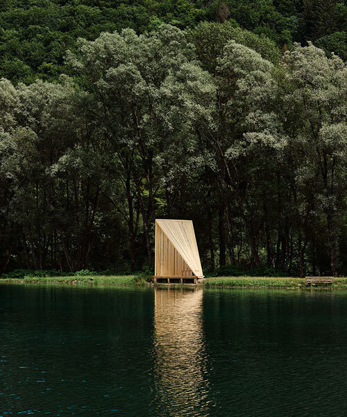 triangular wooden cabin unfolds on river's shore near alps as a fishermen's retreat