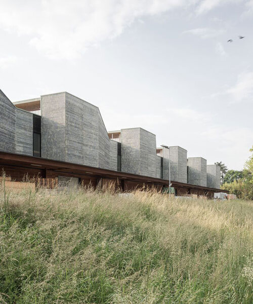 seven wood-clad boxes set in rhythmic sequence outline industrial building's facade in italy