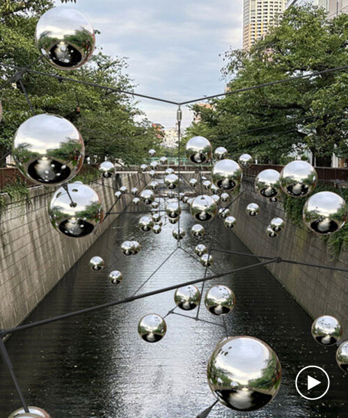 reflective spheres by vincent leroy form swirling constellation above canal in tokyo