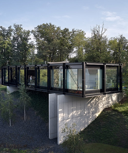 stempel & tesar architekti's 'villa sidonius' is a steel bridge across massive concrete pillars