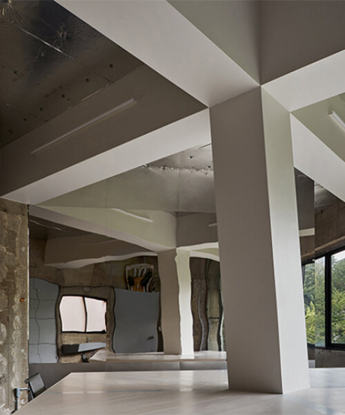 intersecting beams and large table divide yet connect workers at compact office in tokyo