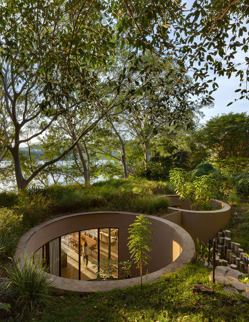 Los vacíos circulares en una casa ecológica diseñada por MCxA Group abrazan los árboles ancestrales de México
