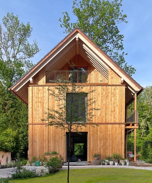 towering poplars, pines, and firs shield studiomolter’s wooden house by the river in germany