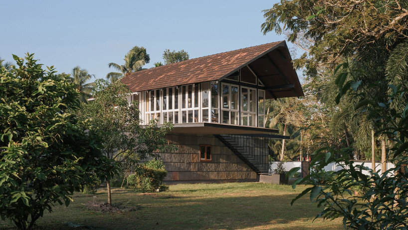 pitched roof volume cantilevers from thomas parambil's house amid kerala paddy fields