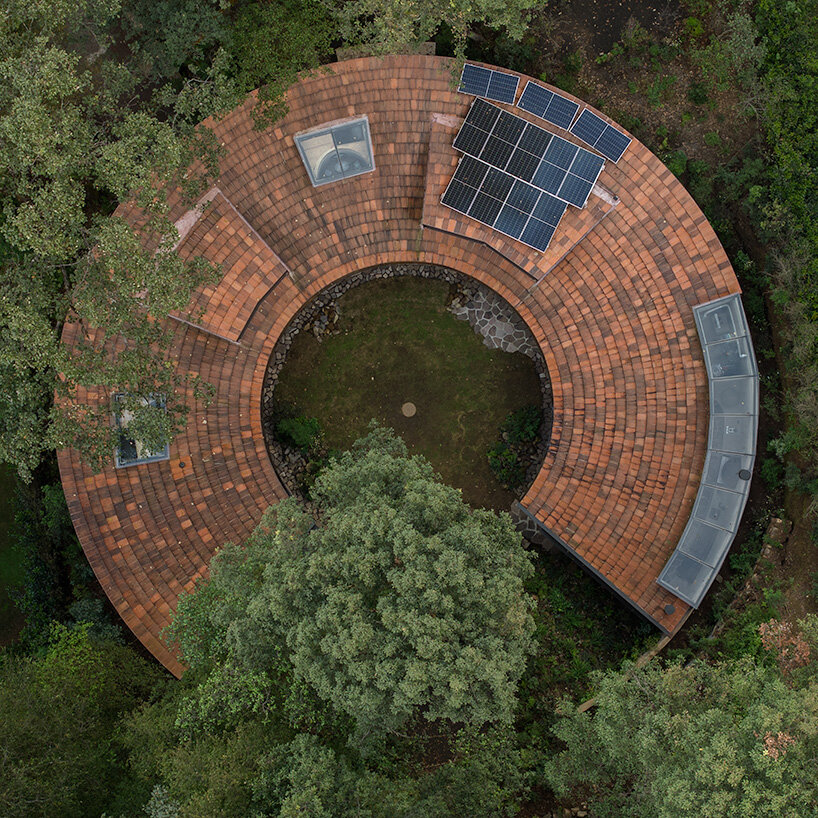 ring structure of casa girasol channels sunlight amid pine forest in mexico