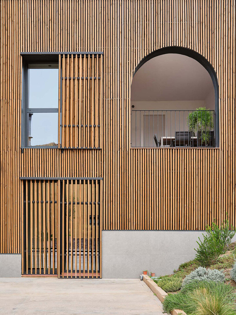 wooden sliding shutters frame arched openings in spanish renovation by sergi pons studio