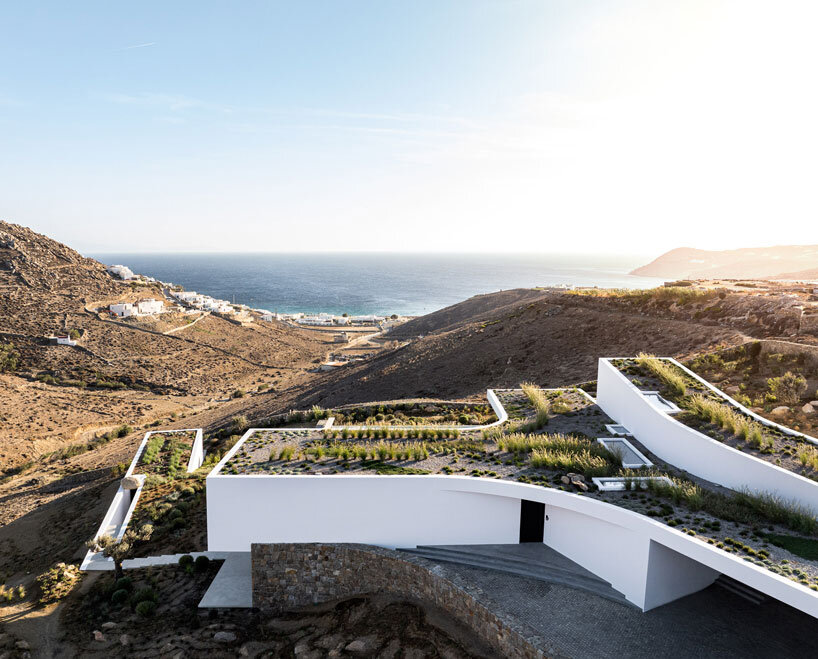 curved dry stone wall outlines villa by A31 and tom dixon emerging from mykonian hillside