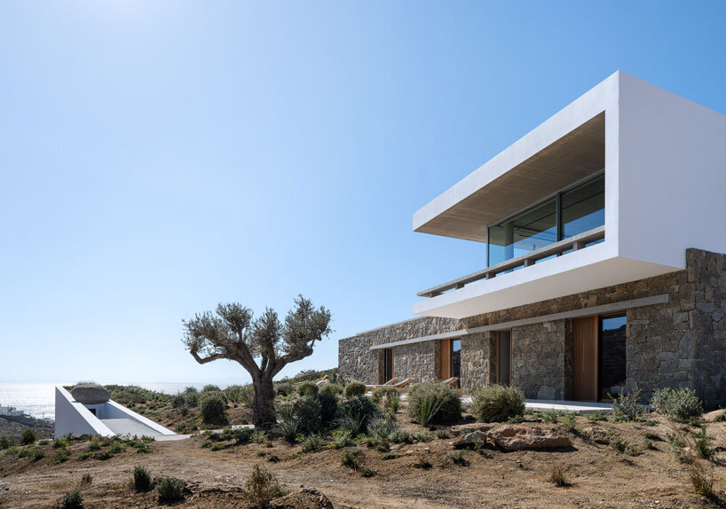 curved dry stone wall outlines villa by A31 and tom dixon emerging from mykonian hillside