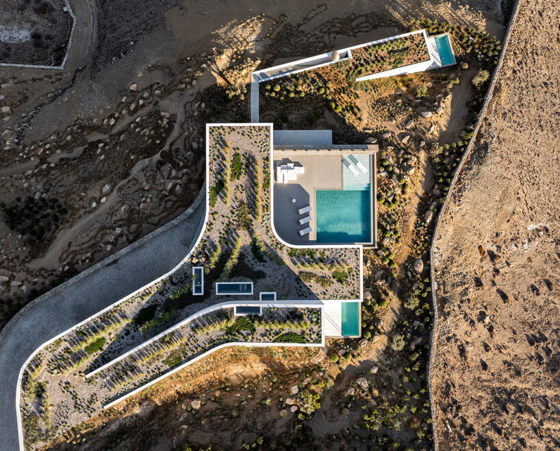 curved dry stone wall outlines villa by A31 and tom dixon emerging from mykonian hillside