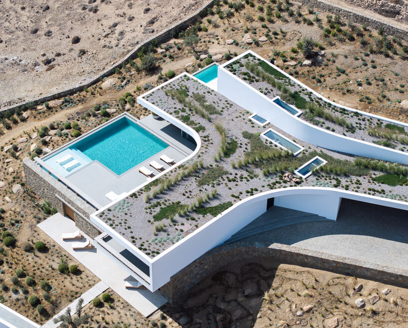 curved dry stone wall outlines villa by A31 and tom dixon emerging from mykonian hillside