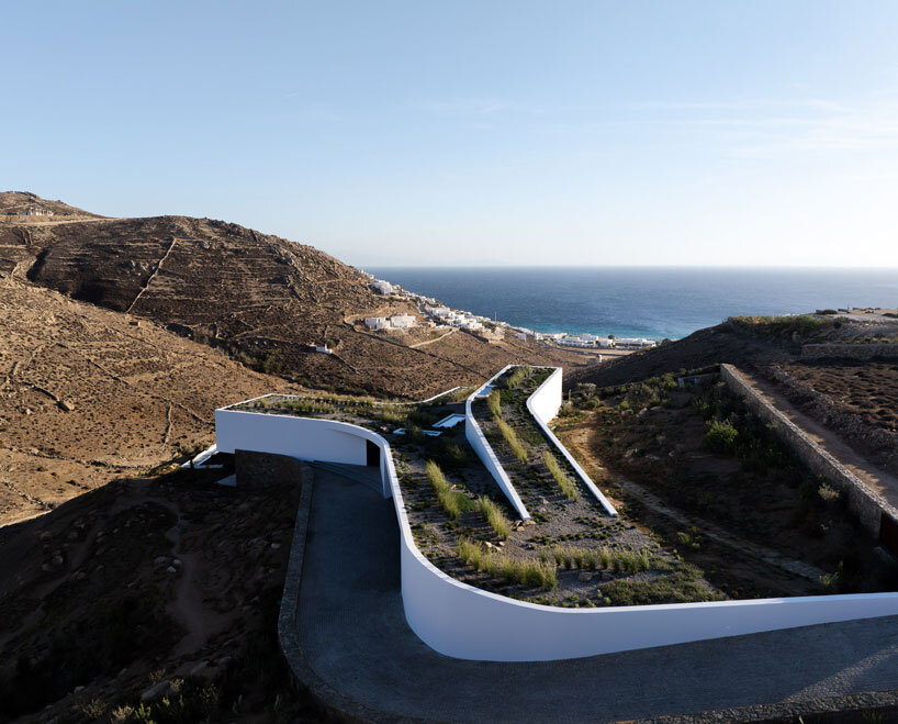 curved dry stone wall outlines villa by A31 and tom dixon emerging from mykonian hillside