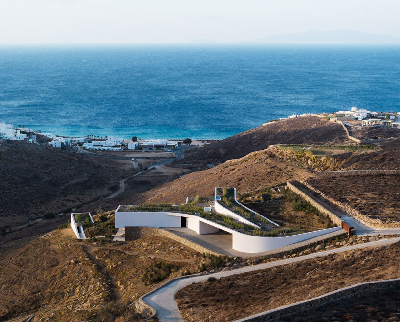 curved dry stone wall outlines villa by A31 and tom dixon emerging from mykonian hillside