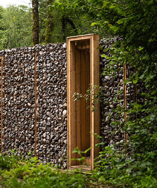 gabion walls frame tephra's stone shelter along dry riverbed in french mineral landscape