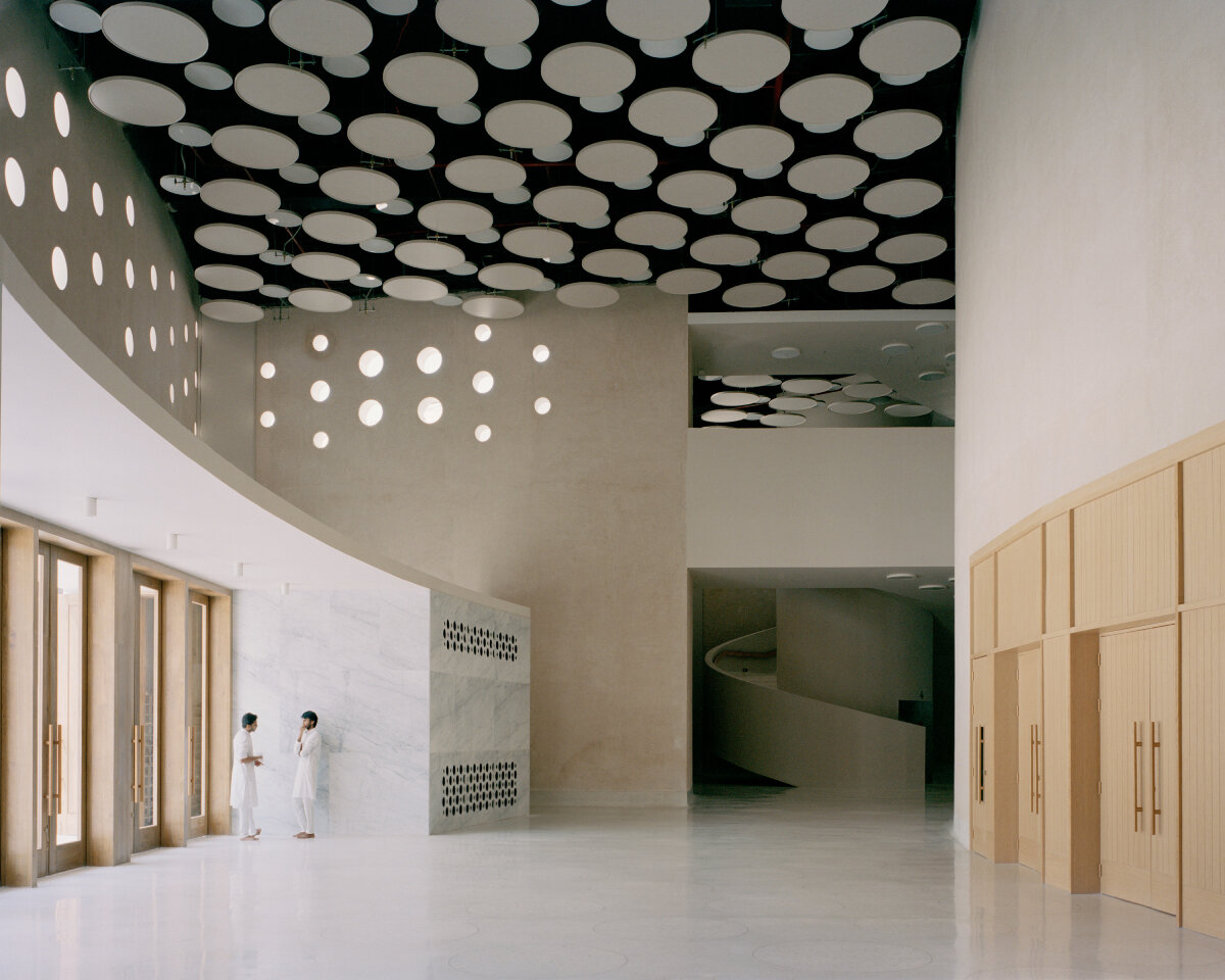 sequence of curved white marble volumes shape serie architects' ashram auditorium in india