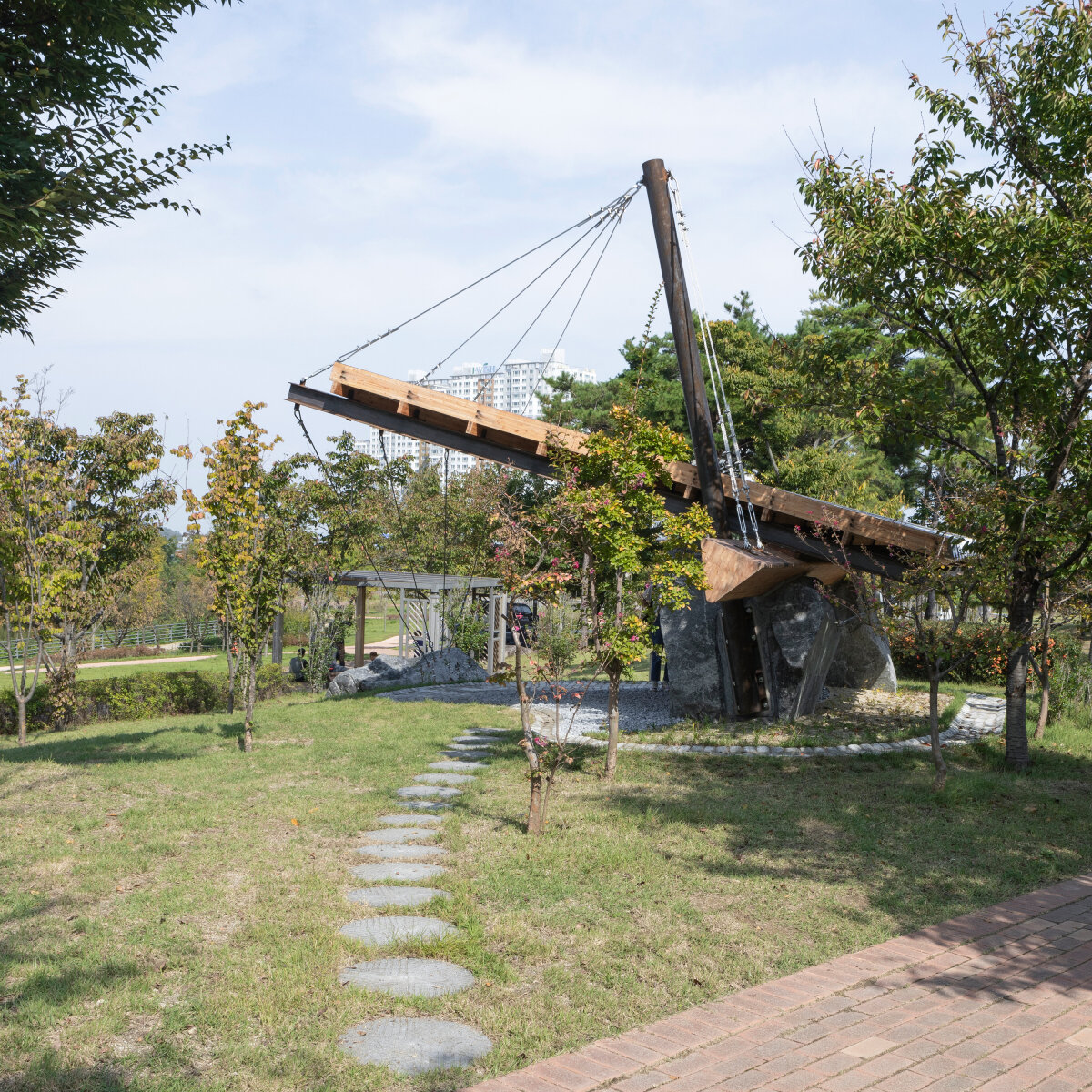 wood & metal canopy rests atop rocks for 'urban interior' installation in south korea
