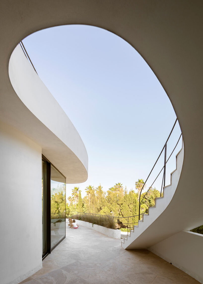 curved white volumes and verdant surroundings define house in les rotes, spain