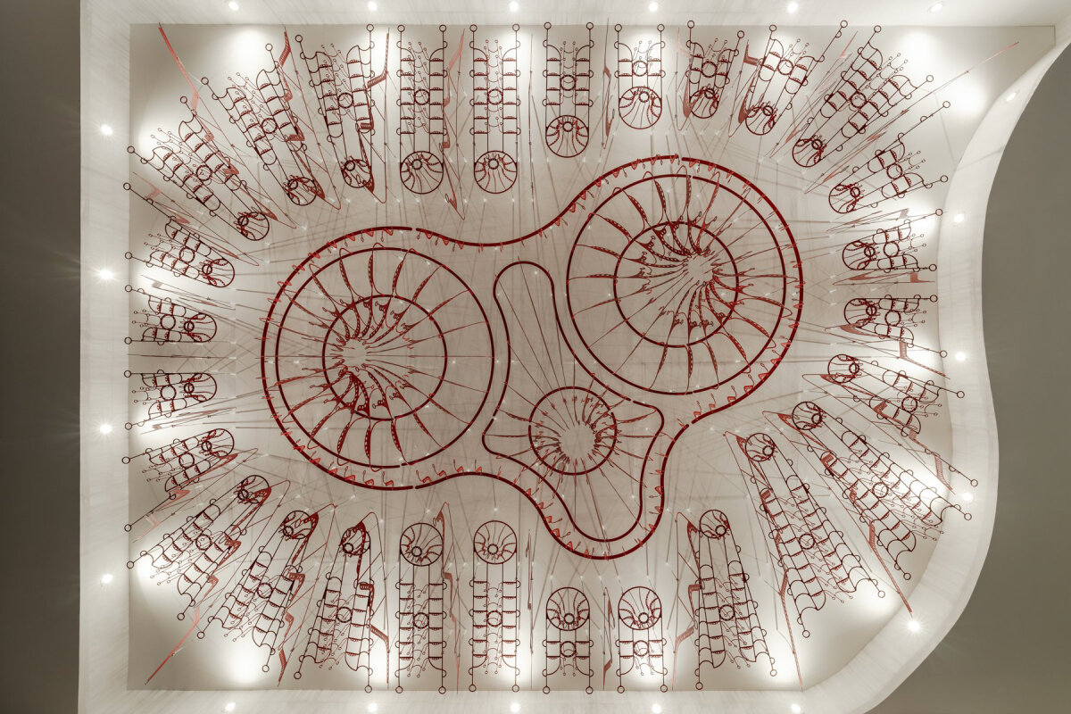 poh sin studio's intricate, industrial red chandelier suspends from malaysia office ceiling