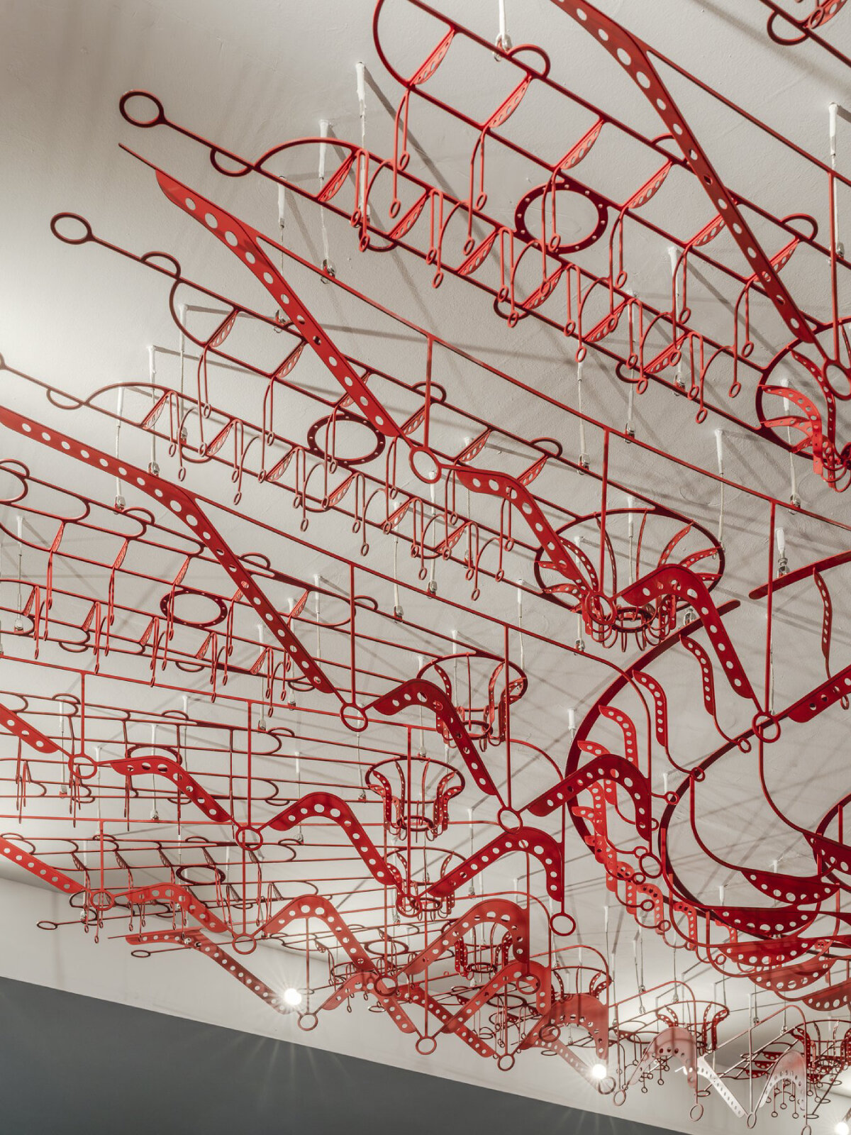 poh sin studio's intricate, mechanical red chandelier suspends from malaysia office ceiling