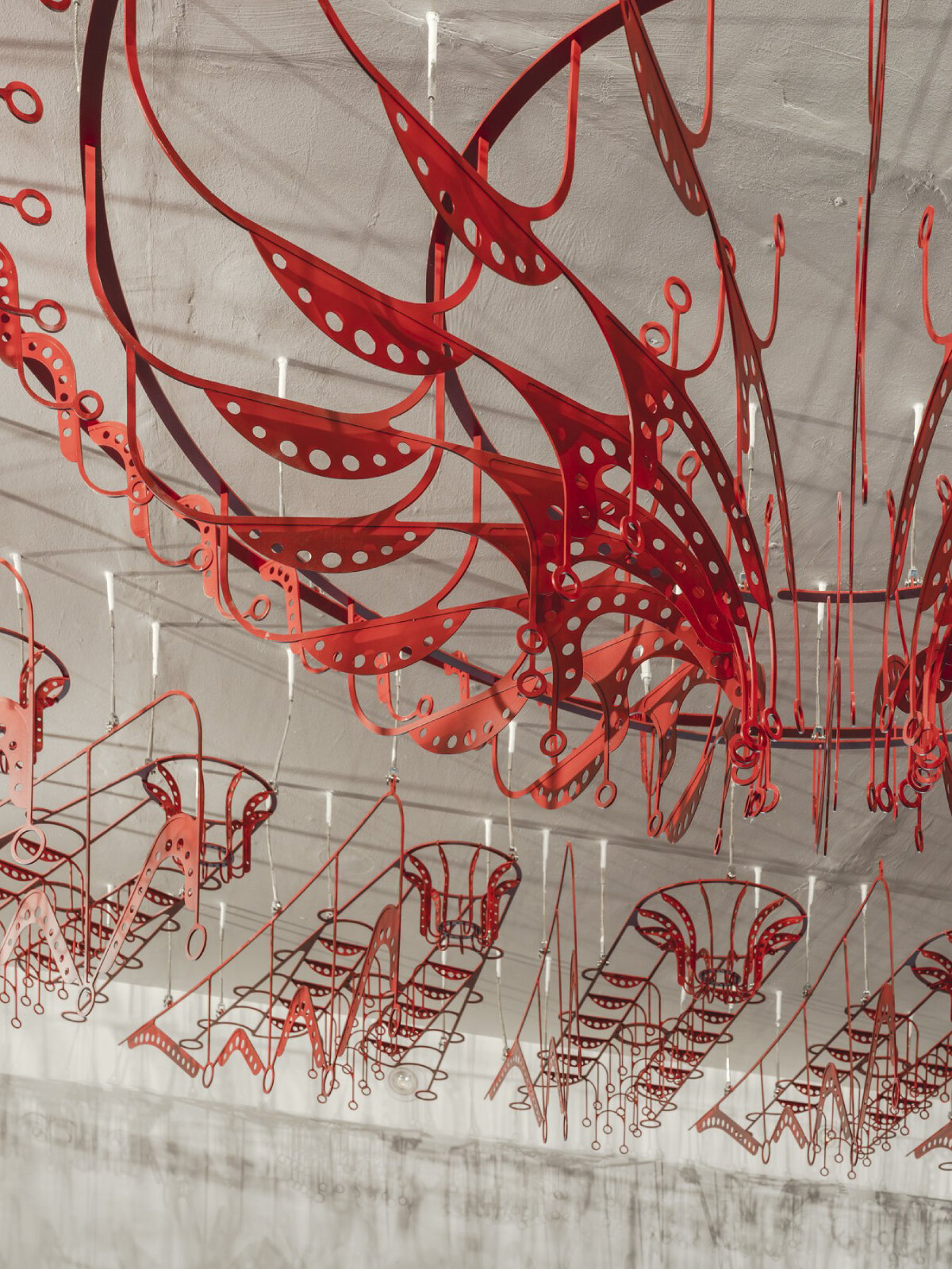 poh sin studio's intricate, mechanical red chandelier suspends from malaysia office ceiling