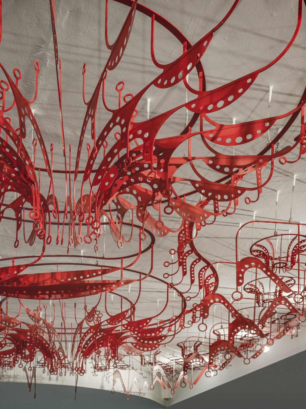 poh sin studio's intricate, mechanical red chandelier suspends from malaysia office ceiling