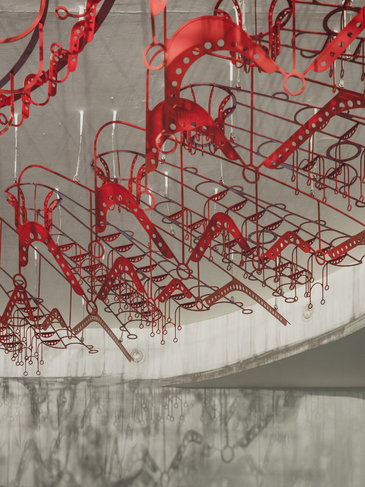 poh sin studio's intricate, mechanical red chandelier suspends from malaysia office ceiling