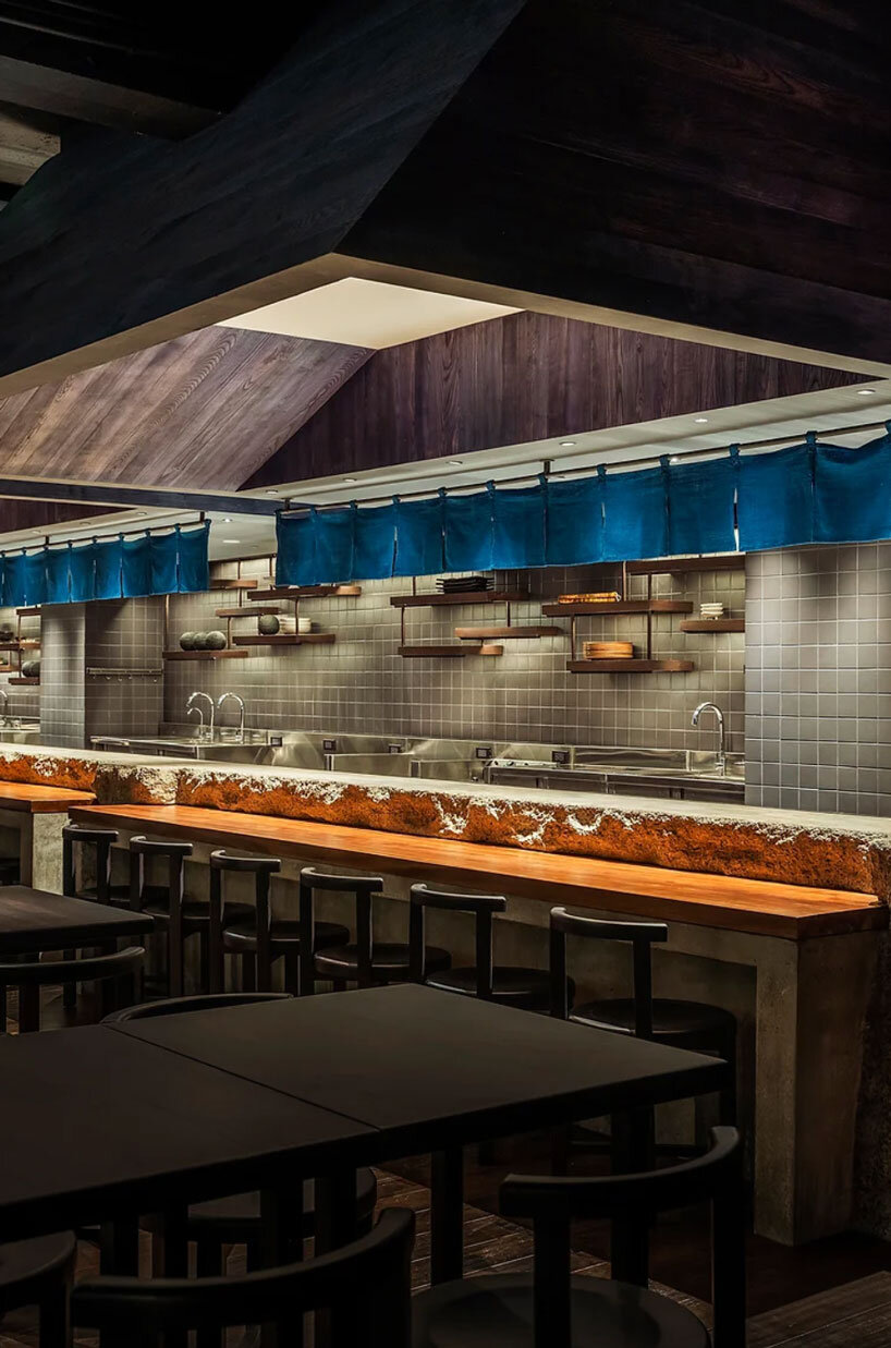 indigo fabric partitions float above sculpted concrete counters in rokusho bar by inrestudio