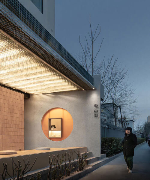 lantern-like lighting shines through suspended metal grid within tea pavilion in beijing