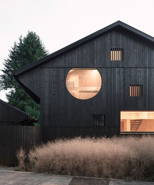 black charred timber cladding envelops twin gabled houses with one pillar in munich