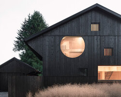 black charred timber cladding envelops twin gabled houses with one pillar in munich