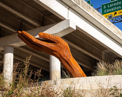 mark reigelman's oversized hand sculpture captures runoff water from overpass in texas