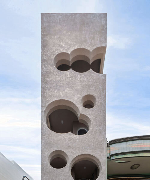 cloud-shaped openings pierce urban co-living unit's concrete facade in vietnam