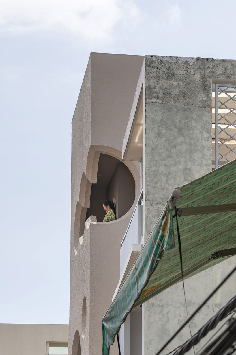 cloud-shaped openings pierce urban co-living unit's concrete facade in vietnam