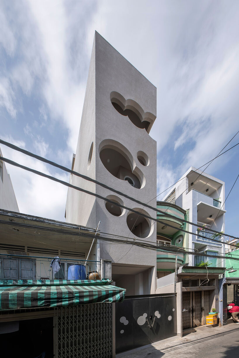 cloud-shaped openings pierce urban co-living unit's concrete facade in vietnam