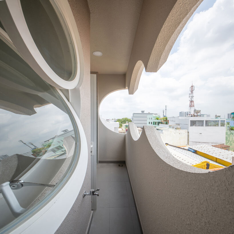 cloud-shaped openings pierce urban co-living unit's concrete facade in vietnam