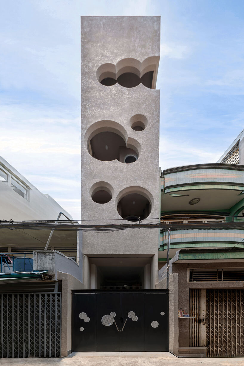cloud-shaped openings pierce urban co-living unit's concrete facade in vietnam